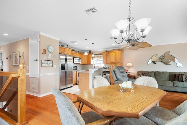 dining room featuring crown molding, light wood-type flooring, and an inviting chandelier