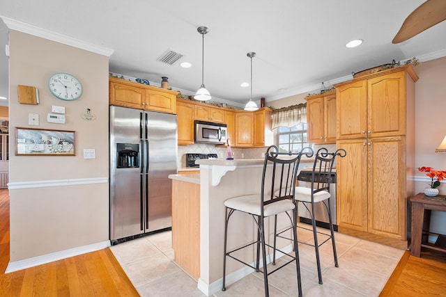 kitchen featuring a center island, crown molding, light tile patterned floors, appliances with stainless steel finishes, and tasteful backsplash