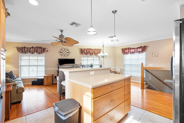 kitchen with stainless steel fridge, plenty of natural light, light tile patterned floors, and a kitchen island