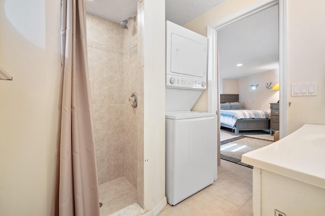 clothes washing area with stacked washer / dryer and light tile patterned floors