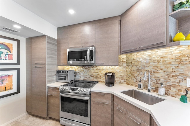 kitchen with stainless steel appliances, light tile patterned floors, sink, and backsplash