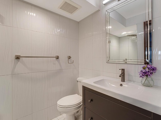 bathroom with vanity, toilet, decorative backsplash, and tile walls