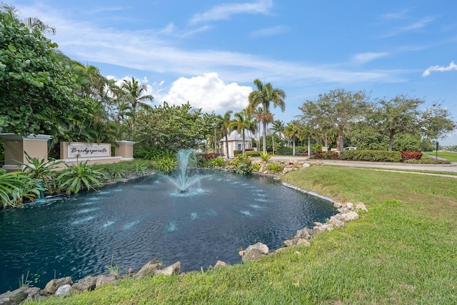 view of home's community with a water view and a lawn