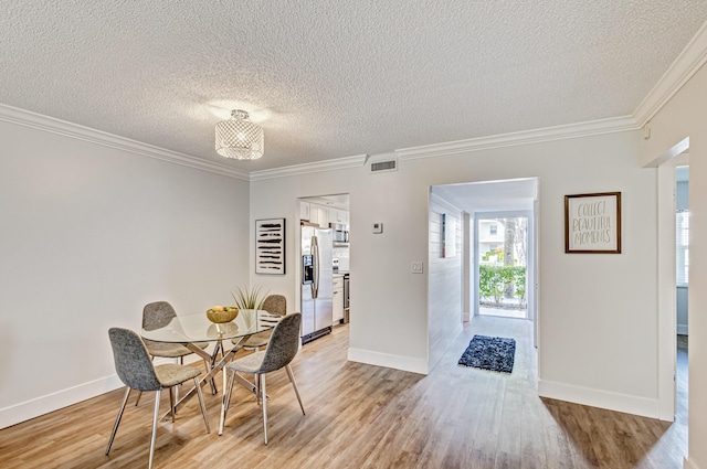 dining area with light wood-type flooring, a textured ceiling, ornamental molding, and baseboards