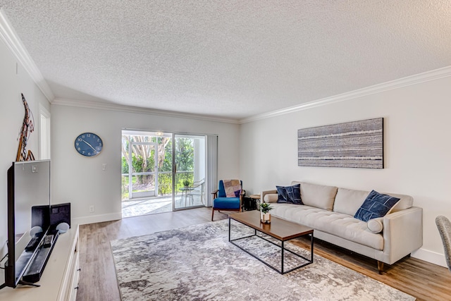 living room with a textured ceiling, ornamental molding, wood finished floors, and baseboards