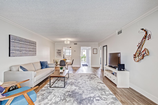 living room featuring a textured ceiling, wood finished floors, crown molding, and baseboards