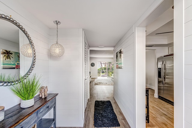 corridor featuring wood finished floors and a chandelier