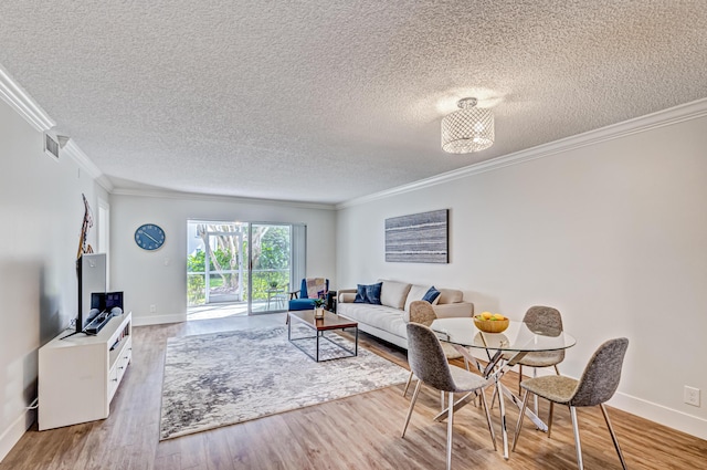 living room featuring crown molding, baseboards, wood finished floors, and a textured ceiling