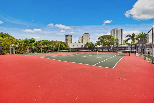 view of tennis court with fence and a city view