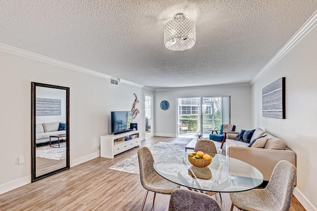 dining space with a textured ceiling, ornamental molding, light wood-type flooring, and baseboards