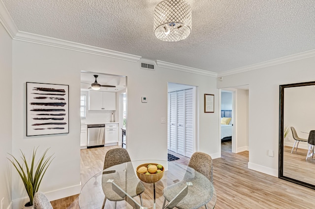 dining room featuring a textured ceiling, light wood finished floors, crown molding, baseboards, and a ceiling fan