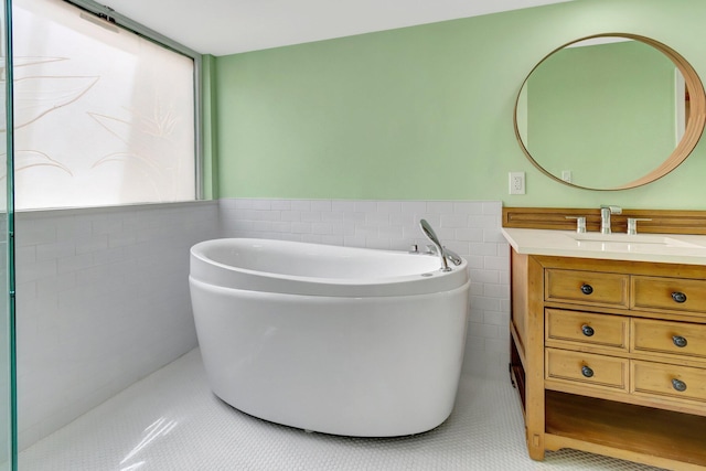 bathroom featuring tile patterned floors, vanity, a tub to relax in, and tile walls