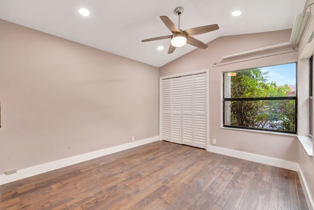 unfurnished bedroom featuring ceiling fan, a closet, wood-type flooring, and lofted ceiling