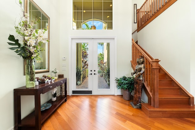 entryway with french doors, a towering ceiling, and wood-type flooring