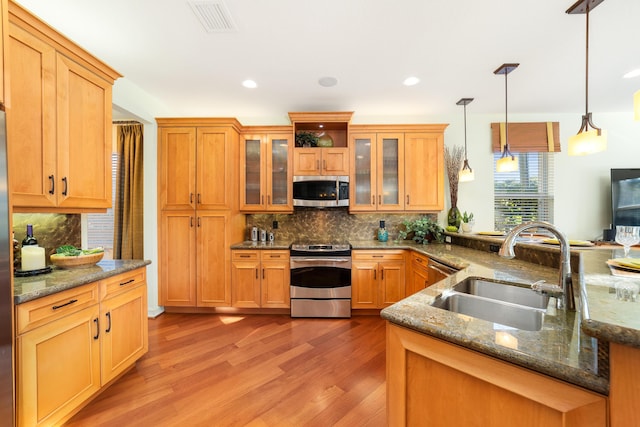 kitchen with pendant lighting, sink, dark stone countertops, and appliances with stainless steel finishes