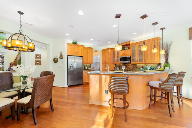 kitchen with pendant lighting, a kitchen bar, decorative backsplash, kitchen peninsula, and stainless steel appliances