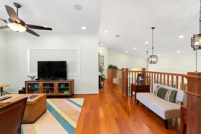 living room with ceiling fan, wood-type flooring, and vaulted ceiling