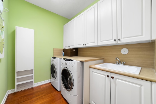 washroom featuring hardwood / wood-style flooring, cabinets, washer and clothes dryer, and sink