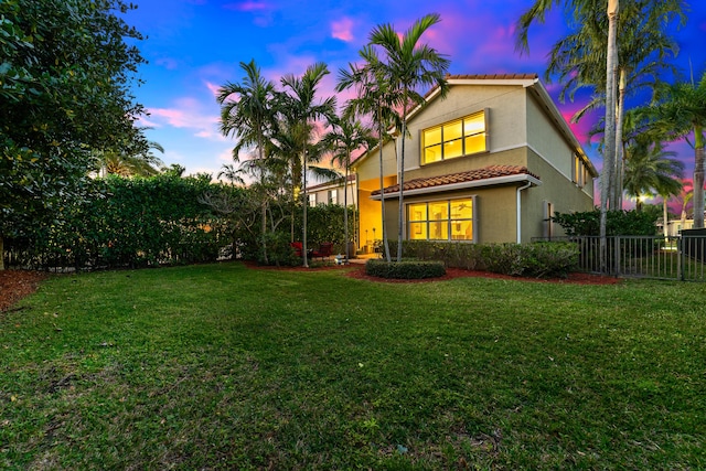 back house at dusk with a lawn