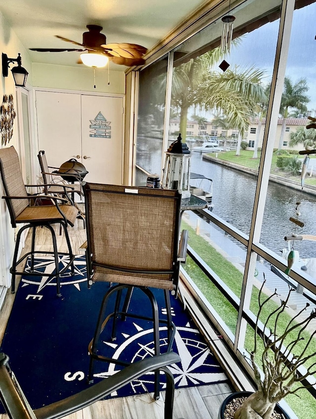 sunroom featuring a water view and ceiling fan