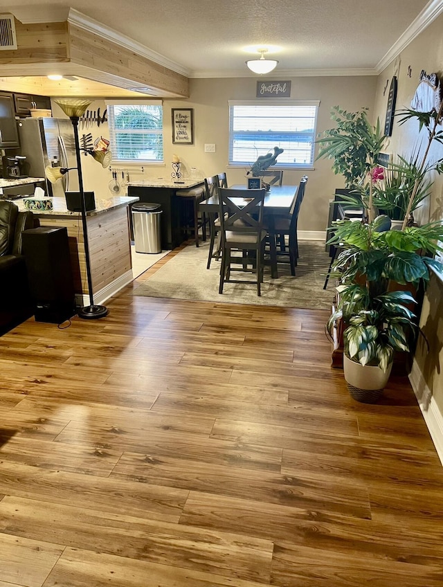 dining area featuring a textured ceiling, light hardwood / wood-style floors, and crown molding