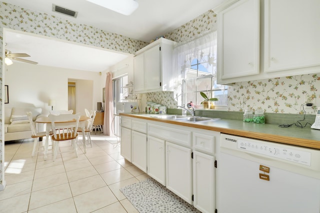 kitchen with white dishwasher, plenty of natural light, white cabinets, and sink