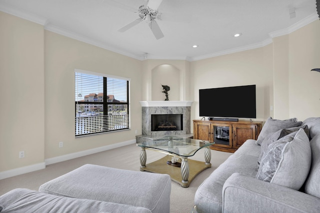 living area with light colored carpet, a ceiling fan, a high end fireplace, baseboards, and ornamental molding