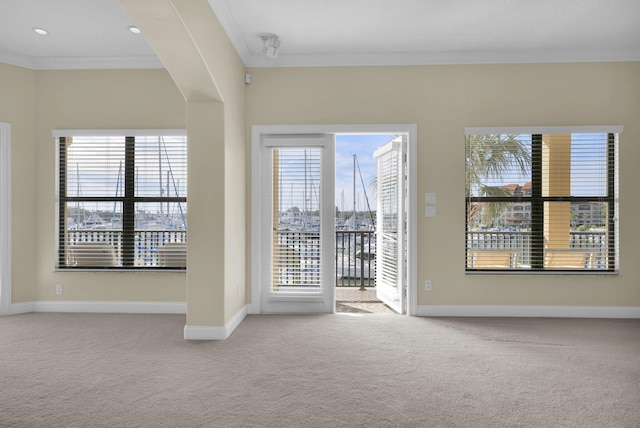 carpeted spare room featuring baseboards and crown molding