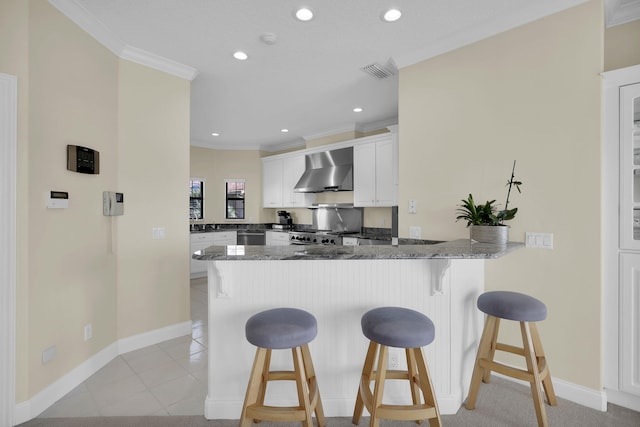 kitchen with wall chimney exhaust hood, a kitchen breakfast bar, kitchen peninsula, crown molding, and white cabinets