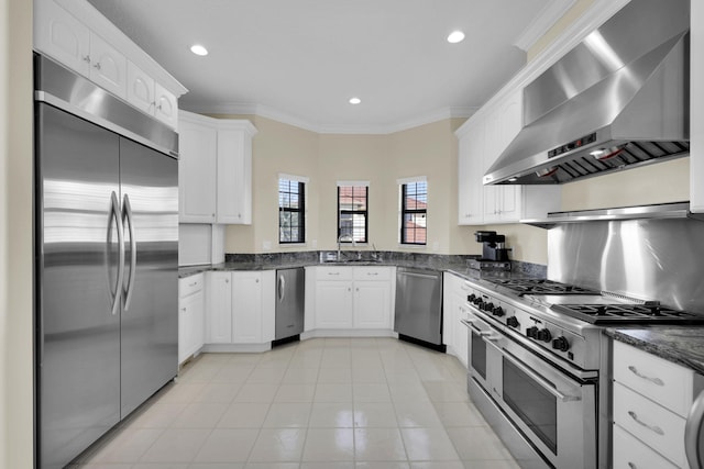 kitchen with wall chimney exhaust hood, white cabinetry, stainless steel appliances, and crown molding