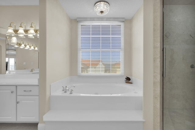 bathroom with a textured ceiling, a garden tub, vanity, and a shower stall