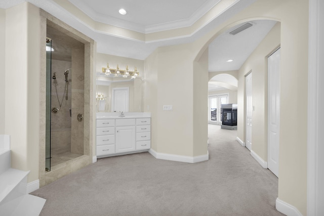 full bath with baseboards, visible vents, tiled shower, crown molding, and vanity