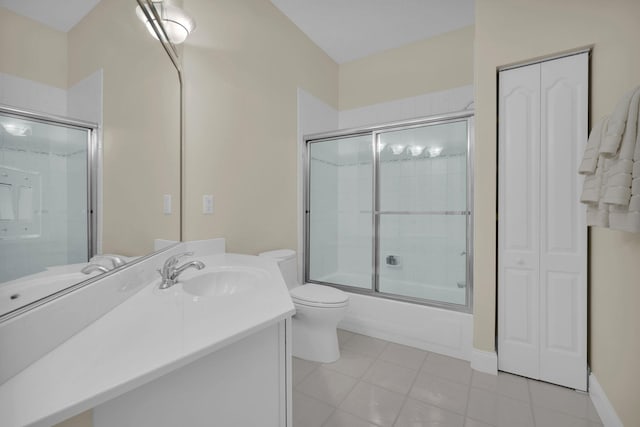 bathroom featuring bath / shower combo with glass door, toilet, vanity, tile patterned flooring, and baseboards