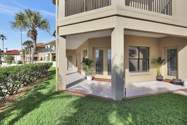 exterior space with a balcony, a yard, a patio, and stucco siding