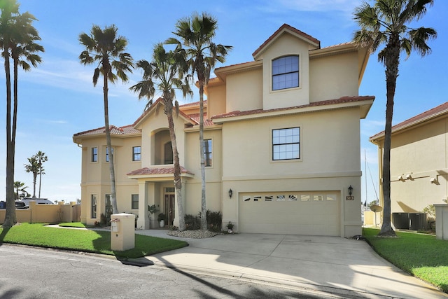 mediterranean / spanish-style house with a garage, concrete driveway, a front yard, and stucco siding