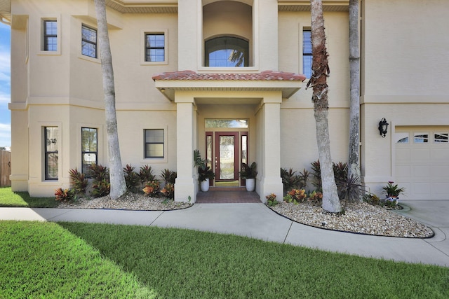 property entrance with a garage, a tile roof, and stucco siding