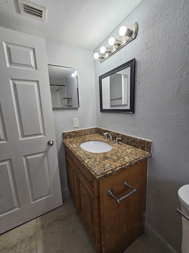 bathroom with tile patterned floors, vanity, a textured ceiling, and toilet