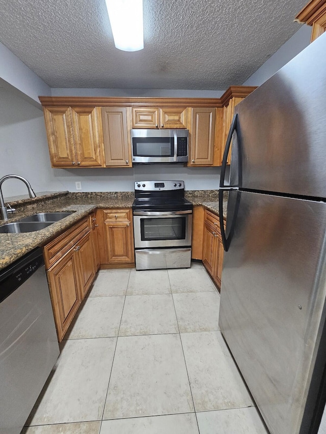 kitchen featuring appliances with stainless steel finishes, a textured ceiling, light tile patterned floors, and sink