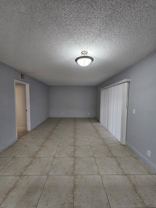 tiled empty room featuring a textured ceiling