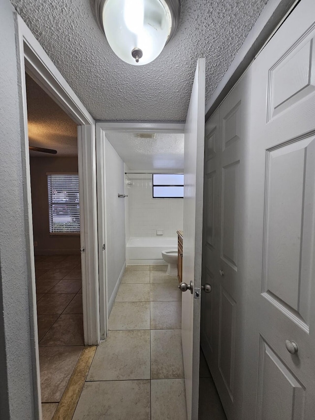 hallway featuring light tile patterned flooring and a textured ceiling