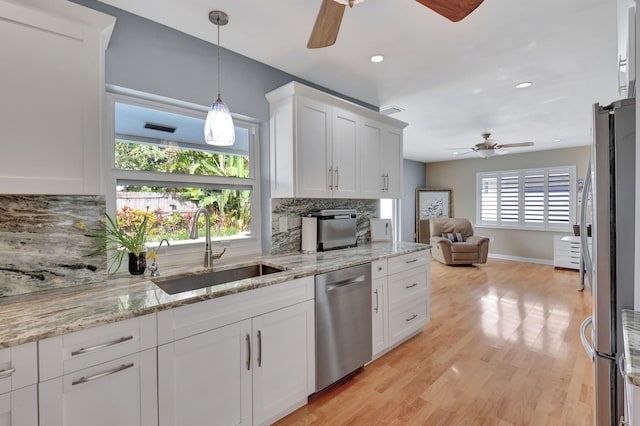 kitchen with sink, white cabinets, tasteful backsplash, light hardwood / wood-style flooring, and appliances with stainless steel finishes