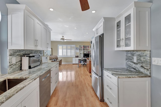 kitchen featuring white cabinets, tasteful backsplash, light hardwood / wood-style flooring, and appliances with stainless steel finishes