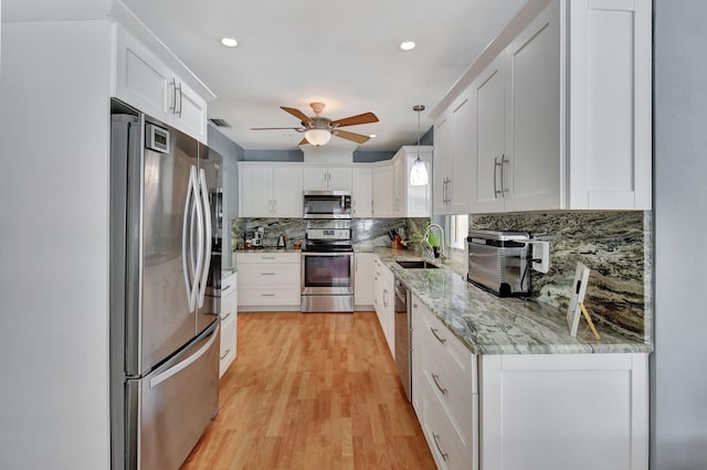 kitchen with pendant lighting, decorative backsplash, white cabinets, appliances with stainless steel finishes, and ceiling fan