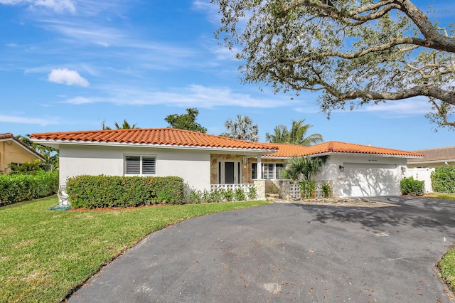 mediterranean / spanish home featuring a front yard and a garage