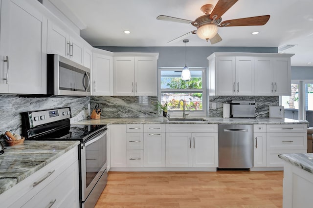 kitchen with white cabinets, appliances with stainless steel finishes, light hardwood / wood-style flooring, and sink