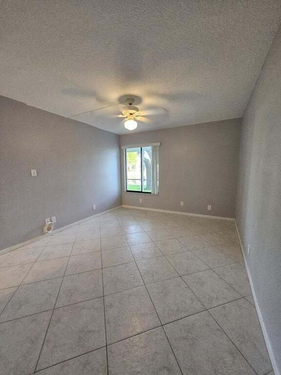 tiled spare room featuring a textured ceiling and ceiling fan