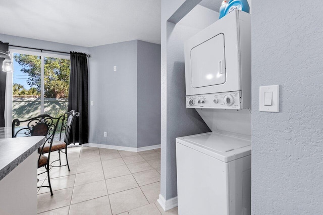 laundry room featuring stacked washer / drying machine and light tile patterned flooring