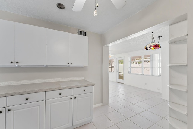 kitchen featuring a textured ceiling, ceiling fan, light tile patterned floors, white cabinetry, and hanging light fixtures