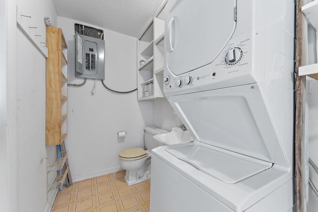 bathroom with electric panel, sink, stacked washer and dryer, toilet, and a textured ceiling