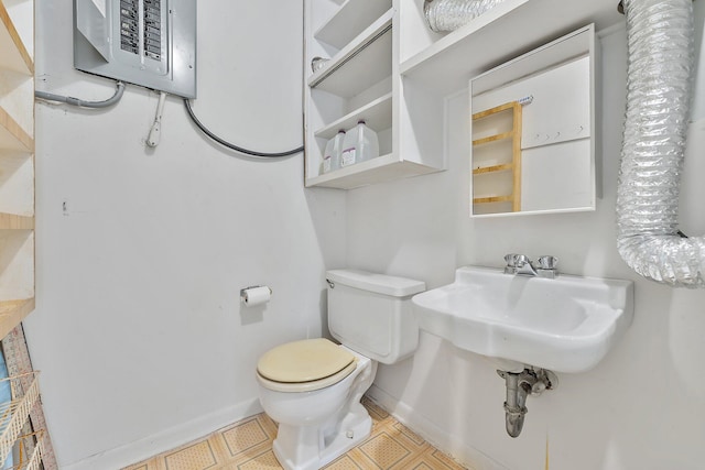 bathroom featuring electric panel, sink, and toilet